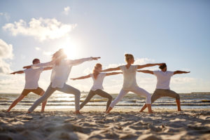 Menschen praktizieren Yoga an der Nordsee am Strand.